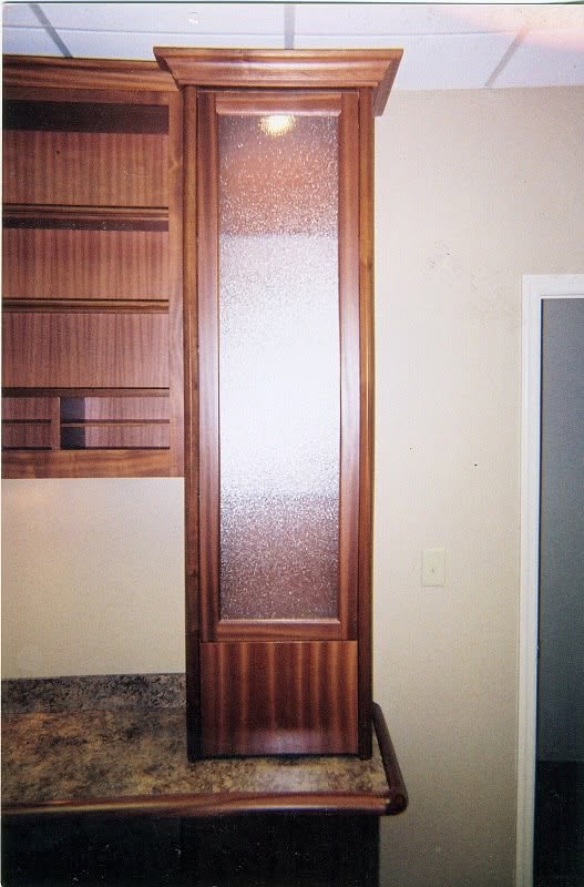 Mahogany display column with textured-glass door beside a granite bar