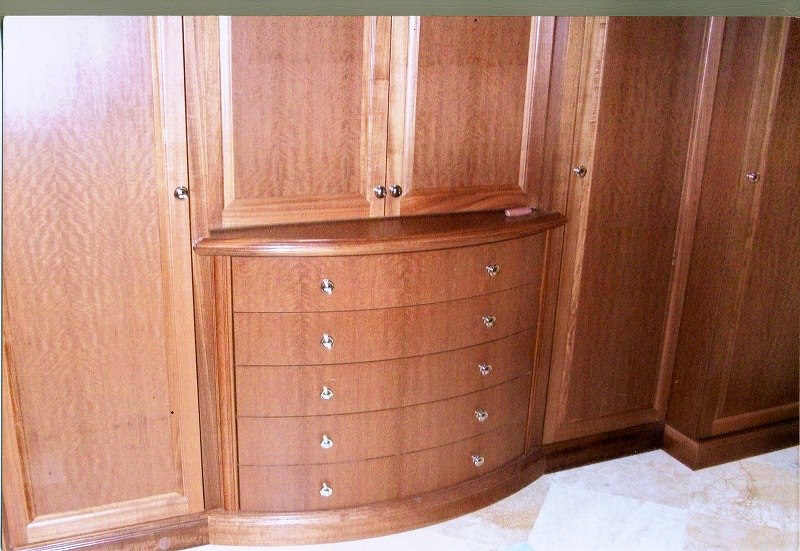 Wardrobe wall with curved drawers and full-height doors