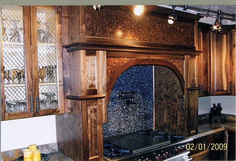 Diamond-mesh glass cabinets flanking a walnut range arch