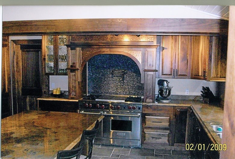 Walnut kitchen with a hand-shaped arched range mantel and copper backsplash