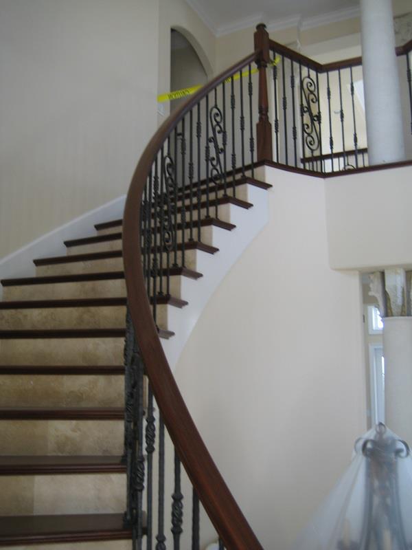 Sweeping hardwood rail over wrought-iron scrollwork