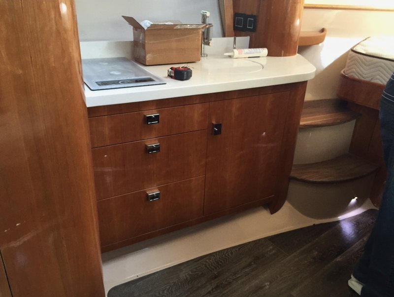 Cherry galley cabinetry with a cooktop, drawers and stone counter