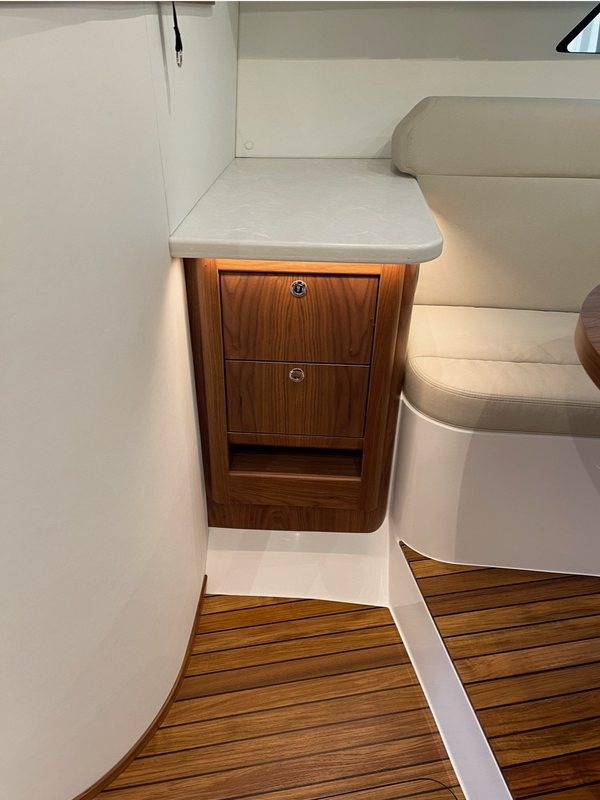 Walnut nightstand cabinet beside a leather settee over teak sole