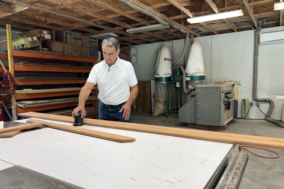 Jahija Ahmic sanding a solid cherry board smooth at his shop bench