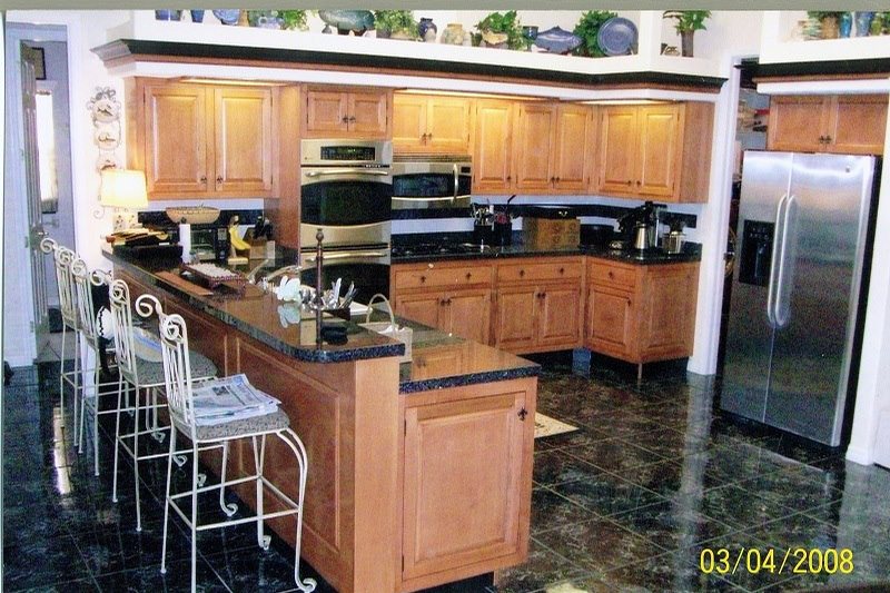 A custom maple kitchen with a black granite island, wall ovens, and glass-front upper cabinets