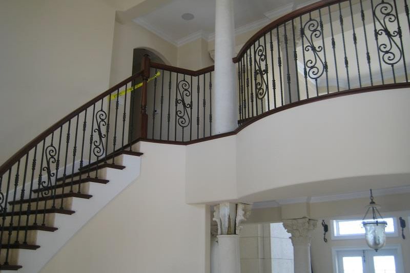 A two-story stair hall with a wood-capped iron balustrade and scrolled balusters