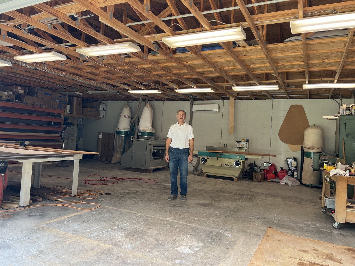 Jahija Ahmic standing in his shop among the sliding table saw, jointer, and wide-belt sander